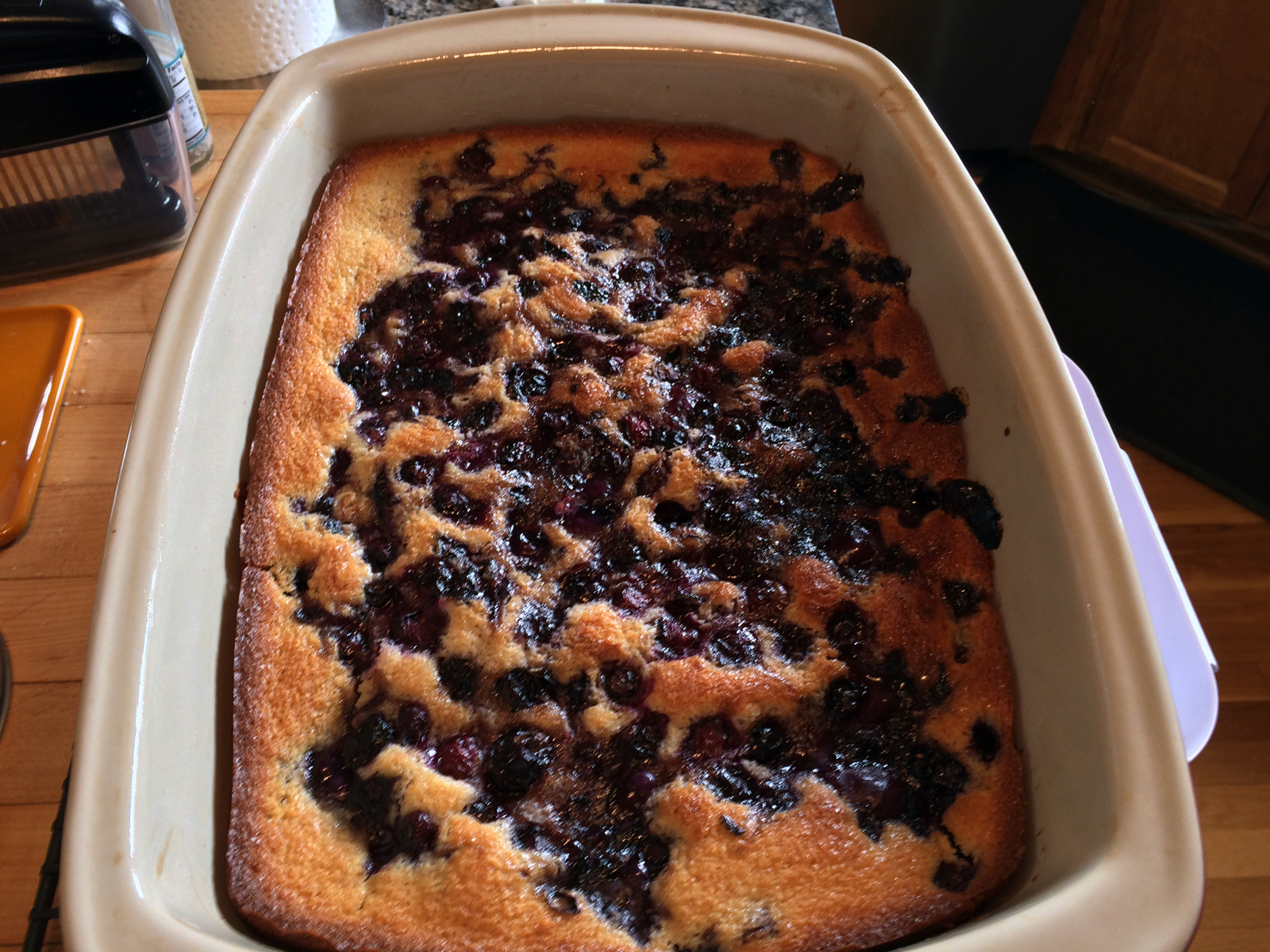 Golden-brown berry cobbler cake with a crispy sugar topping, bubbling with vibrant blueberries and raspberries.