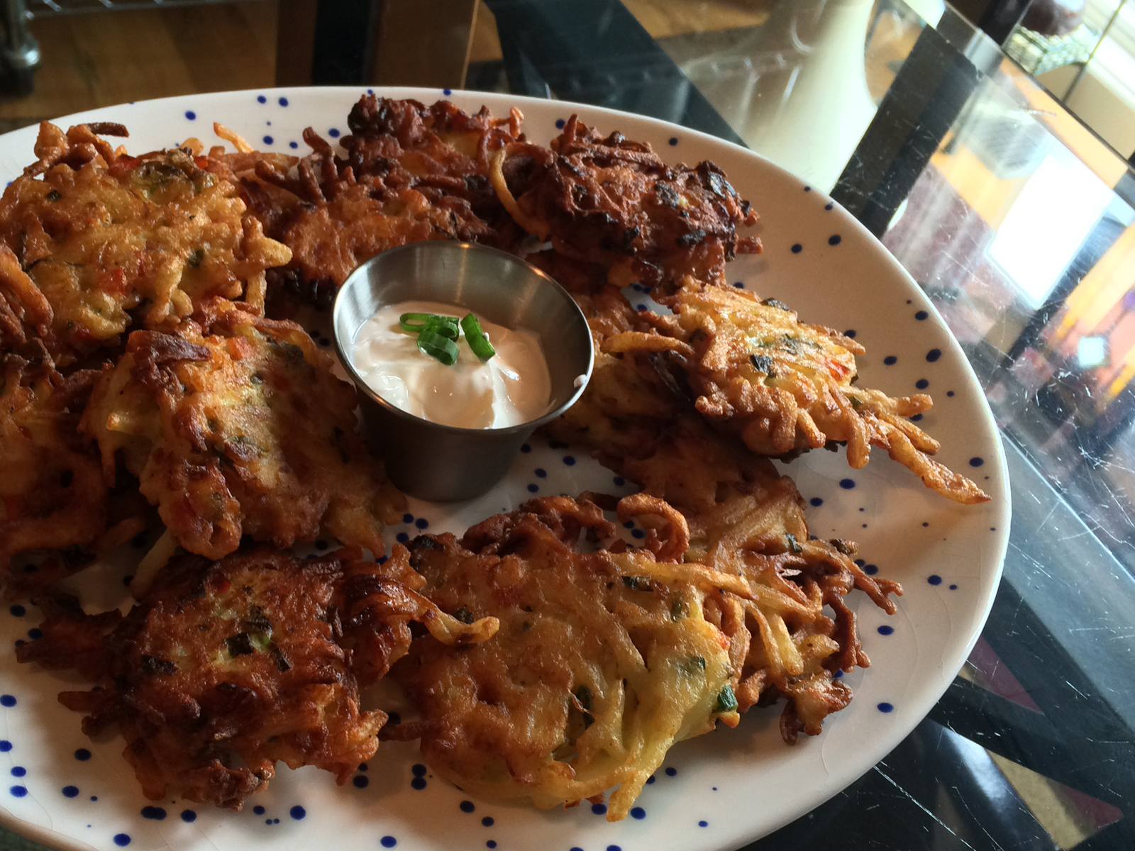 Golden-brown shredded potato cakes with crispy edges, topped with chopped scallions and served on a rustic plate.