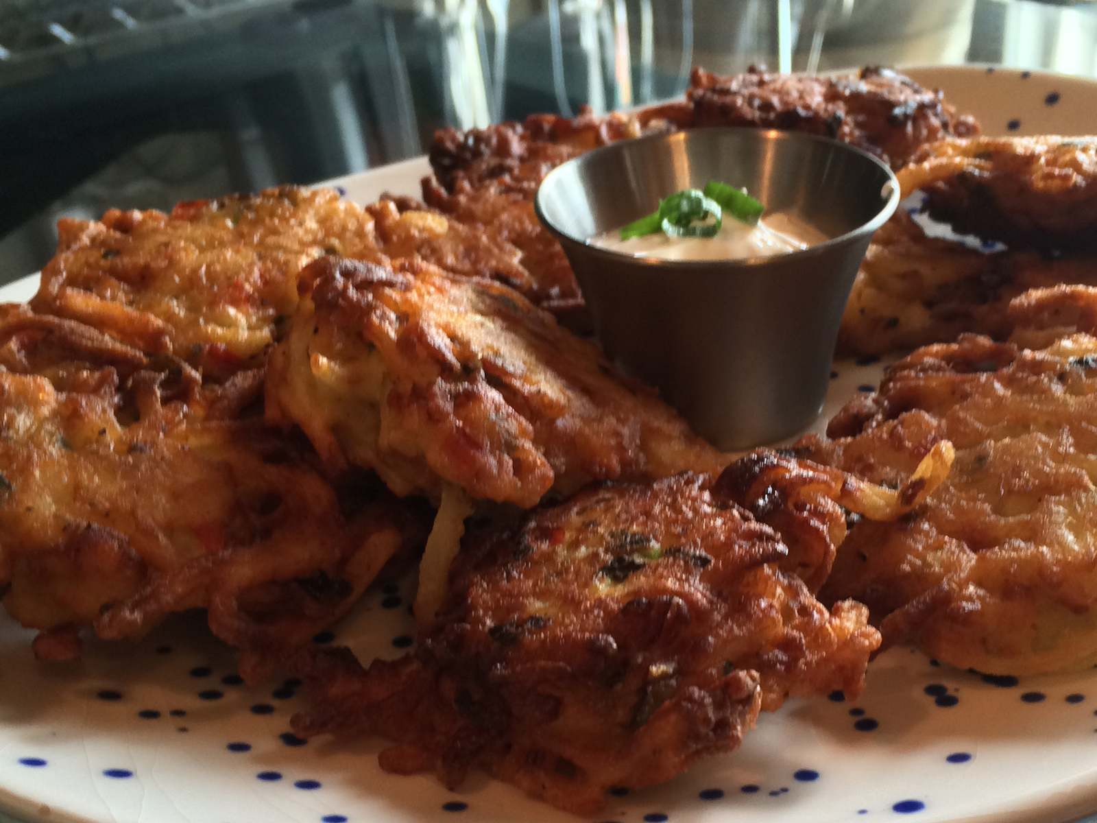 Golden-brown shredded potato cakes with crispy edges, topped with chopped scallions and served on a rustic plate.